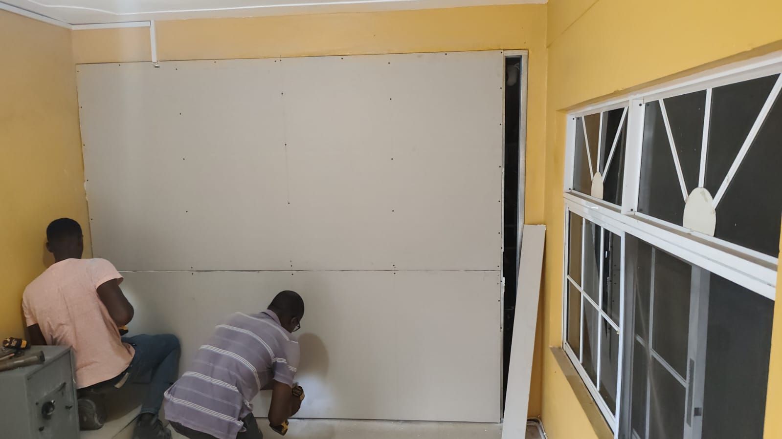 Drywall installation with workers on site